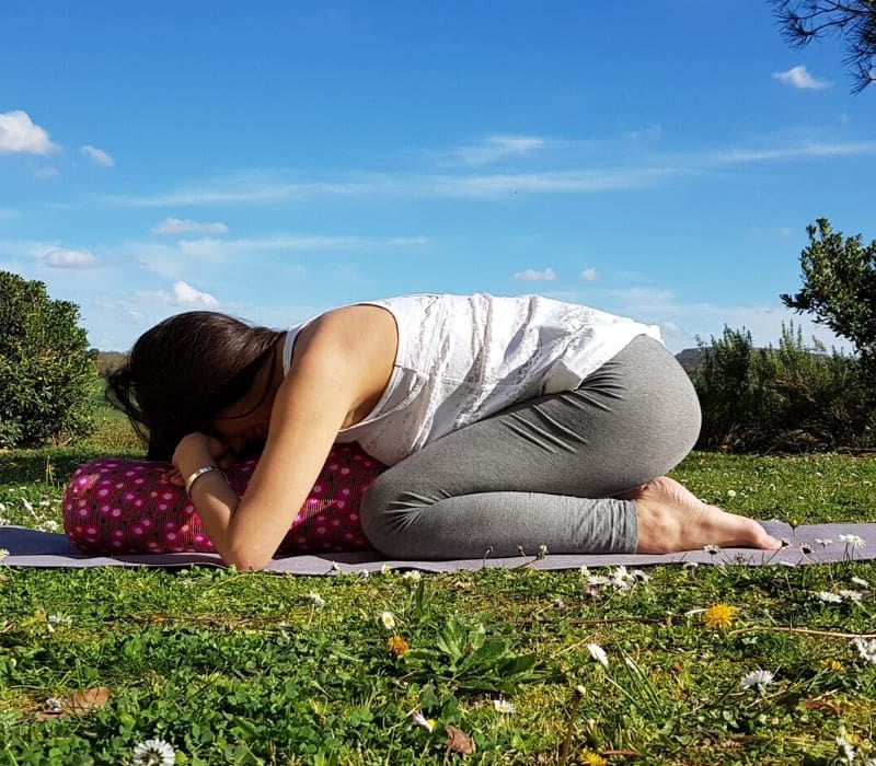La position Balasana, la position de l'enfant avec le bolster La position Balasana, la position de l'enfant avec le bolster